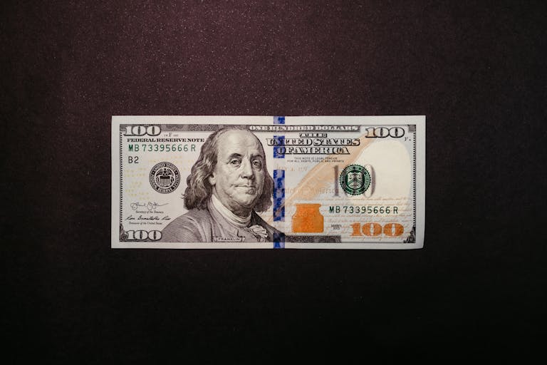 Close-up of a US 100 dollar bill displayed on a black background.