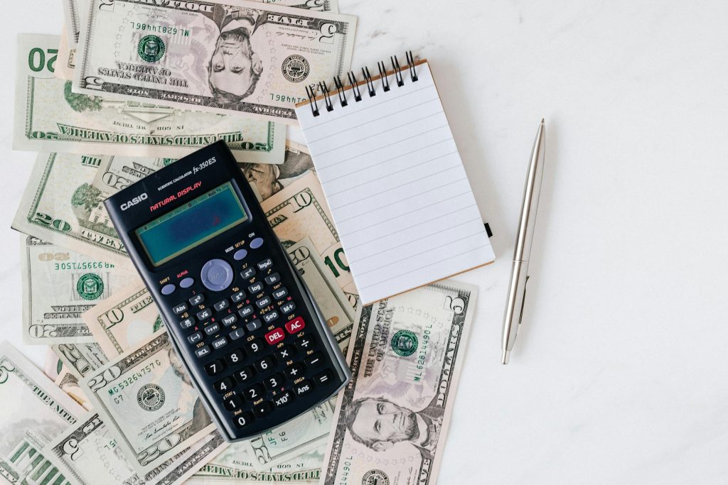 Calculator, notepad, and dollar bills laid out for budgeting