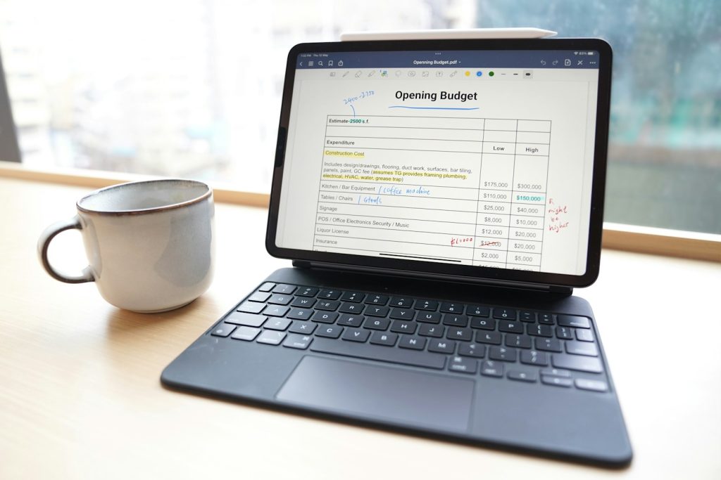 Laptop open to a monthly budget spreadsheet, next to a cup of coffee